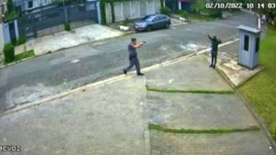 policial apontando arma para homem negro